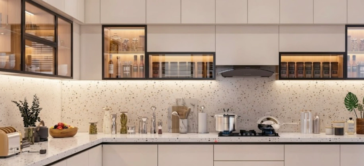 L-shaped modular kitchen design for a compact 2 BHK with glass-front upper cabinets and terrazzo counter